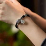 Bracelet artisanal noir, orné de charmantes breloques en cuivre